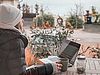 Frau in Winterjacke und Teetasse vor einem Laptop mit Blick zum See